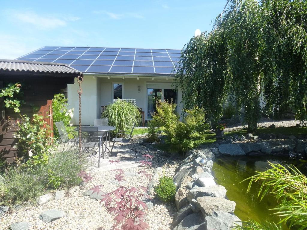 弗兰肯贝格Relaxing Holiday Home in Willersdorf in the forest的池塘顶部设有太阳能电池板的房子