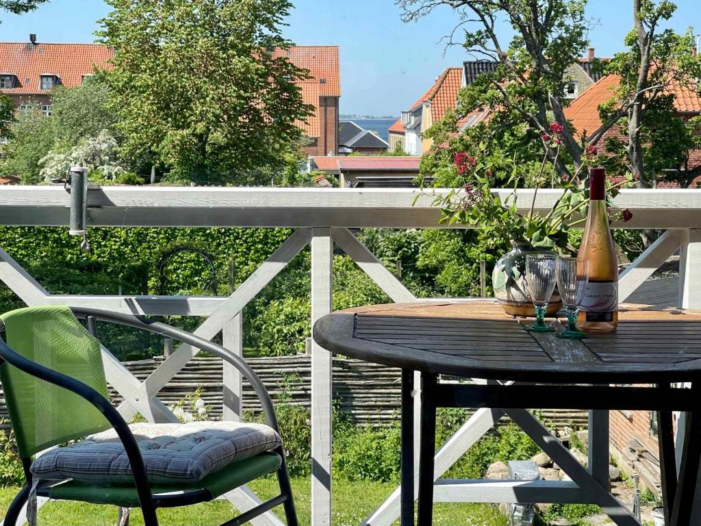 斯泰厄Charmerende Lejlighed I Stege Midtby的阳台上的木桌和一瓶葡萄酒