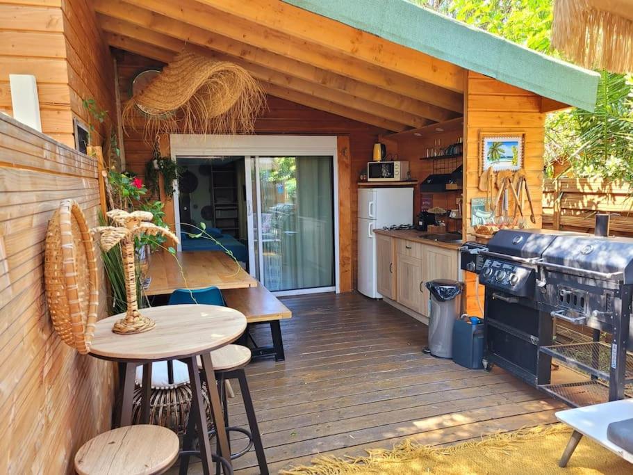弗雷瑞斯Petit chalet avec terrasse proche plage的厨房设有木甲板、桌子和炉灶
