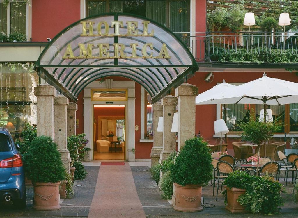特伦托美利坚酒店的一张桌子和遮阳伞的酒店入口