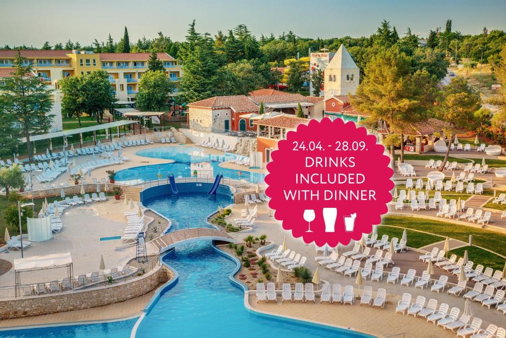 乌马格Residence Garden Istra Plava Laguna的一个带椅子和标志的游泳池的度假酒店