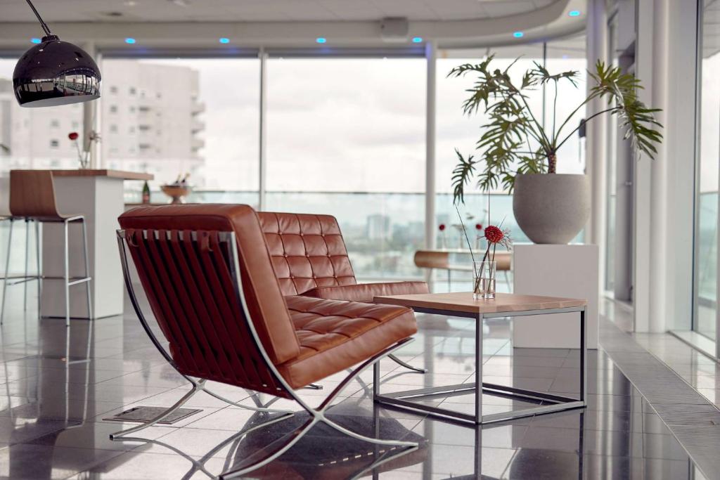 鹿特丹Maashotel Rotterdam Centre的客厅配有真皮座椅和桌子