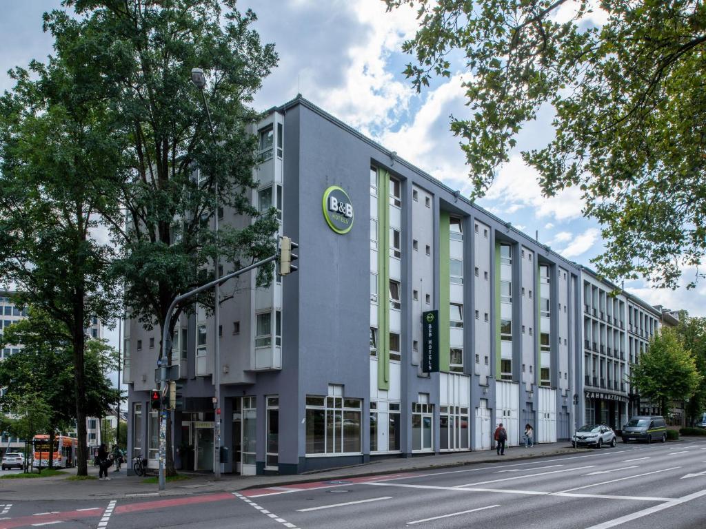 亚琛B&B Hotel Aachen-Hbf的一条白色的大建筑,在街上设有绿色窗户