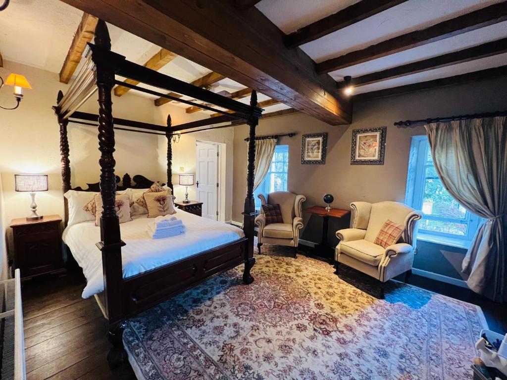 卡斯尔顿Peak Hotel Castleton的一间卧室配有一张天蓬床和两把椅子