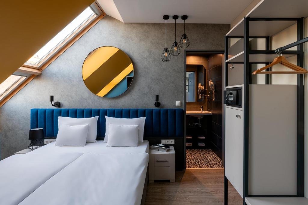 布达佩斯Alta Moda Fashion Hotel的一间卧室配有一张带蓝色床头板和镜子的床