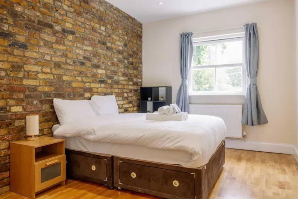 伦敦Bright and Quiet 2-bed 2-bath with Great Patio的一间卧室设有一张带砖墙的大床
