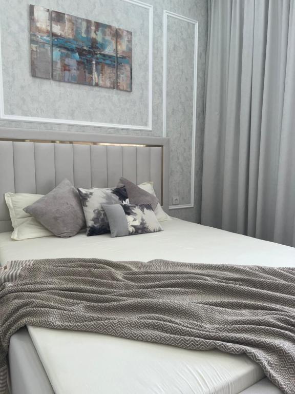 阿斯塔纳Уютная квартира вблизи Байтерека的卧室配有白色的床和枕头。