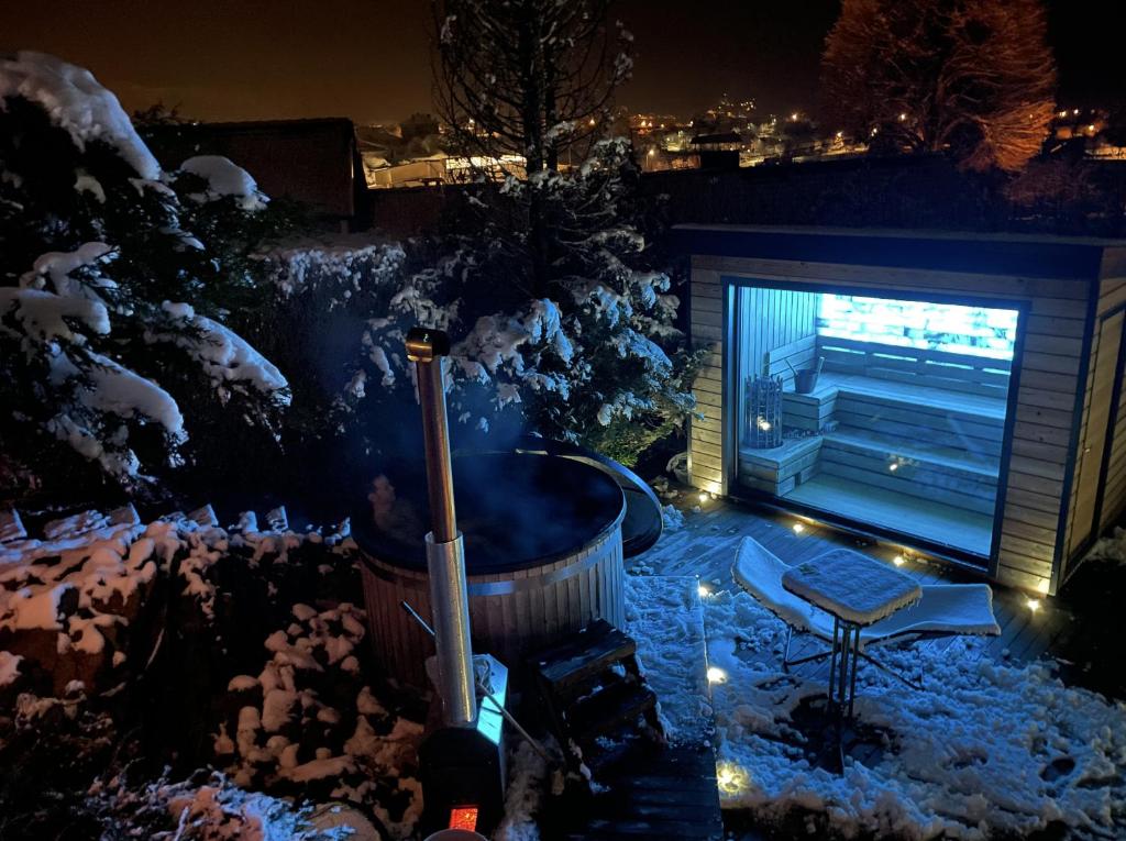 Saint-Étienne-lès-RemiremontL'ANNEXE的一个带热水浴缸和电视的雪覆盖后院