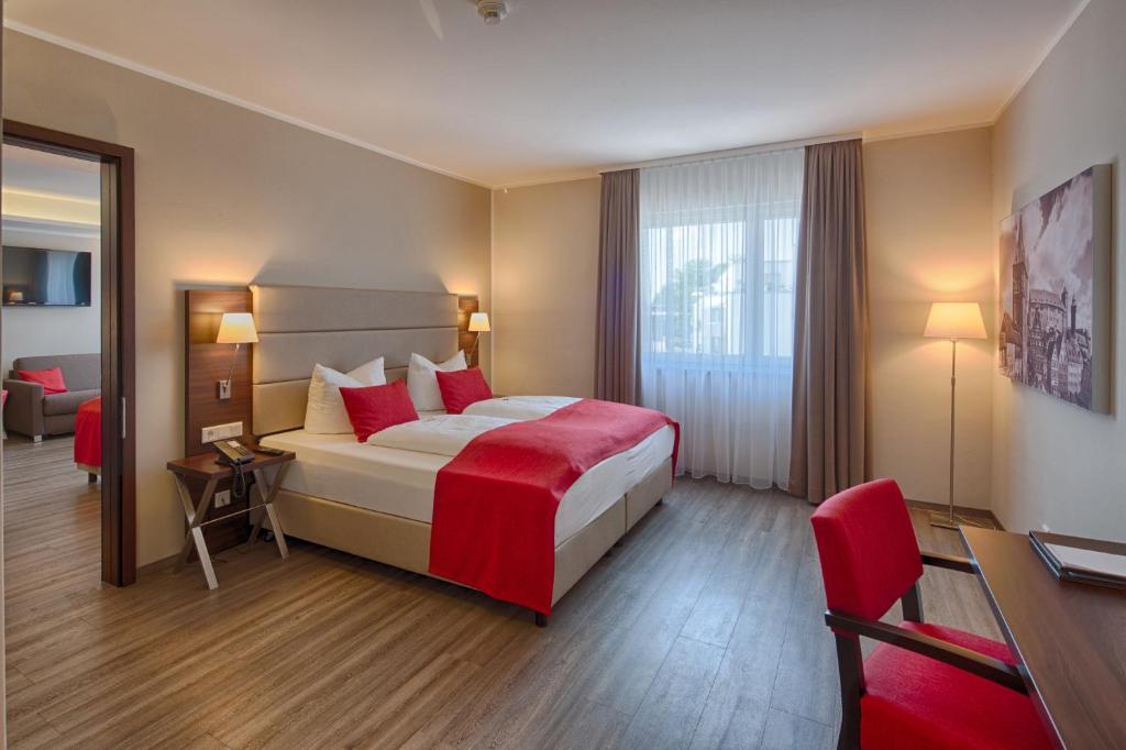 上阿斯巴赫西纽伦堡波蒙提酒店的配有红色枕头的床的酒店客房