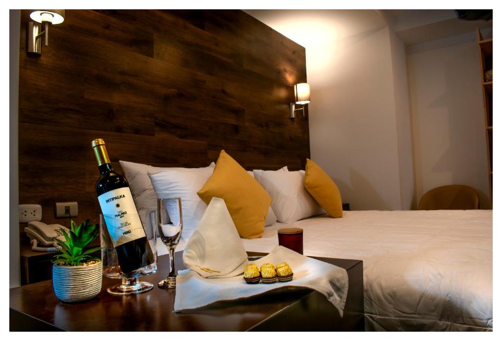 HuancavelicaLA TERRAZA INN的睡床旁的桌子上放一瓶葡萄酒