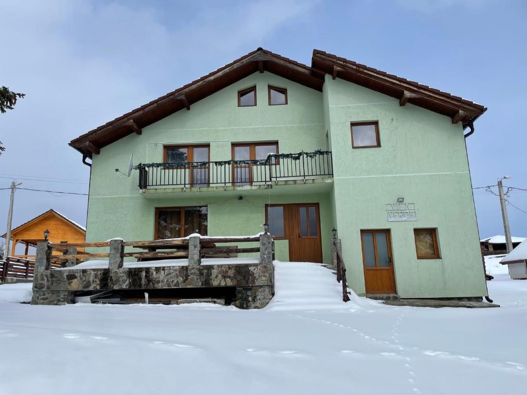 PoplacaVila Verde Păltiniș的雪地中带阳台的绿色房屋