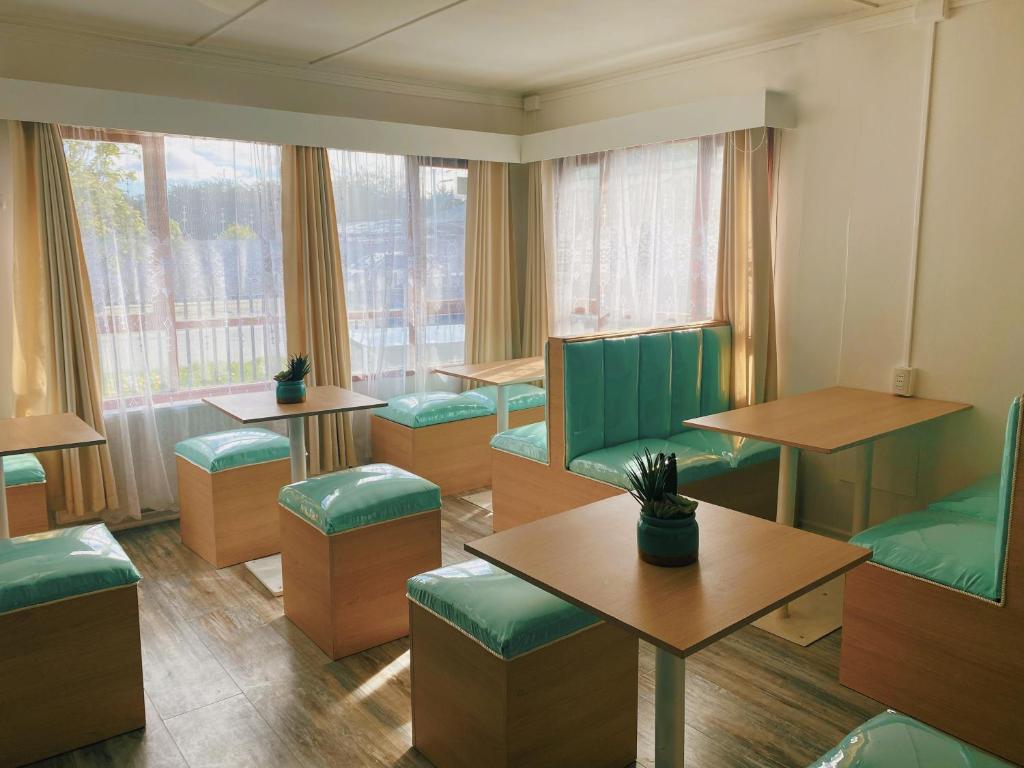 蓬塔阿雷纳斯Indomito Sur Hostel的餐厅设有绿色的桌椅和窗户
