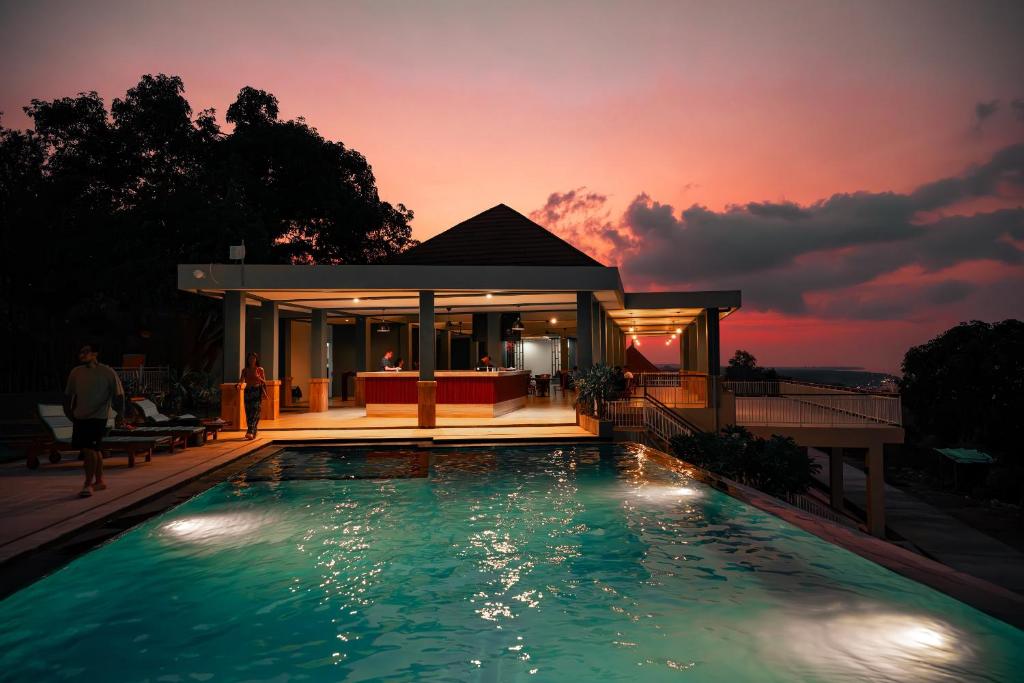 珀尼达岛Jukung Dive Resort Bali PENIDA的日落时在房子前的游泳池