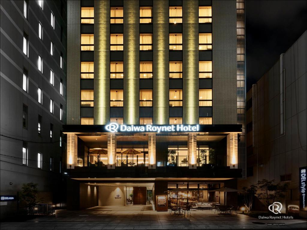 大阪DEL style Osaka-Shinsaibashi by Daiwa Roynet Hotel的一座建筑,有楼房,晚上点燃