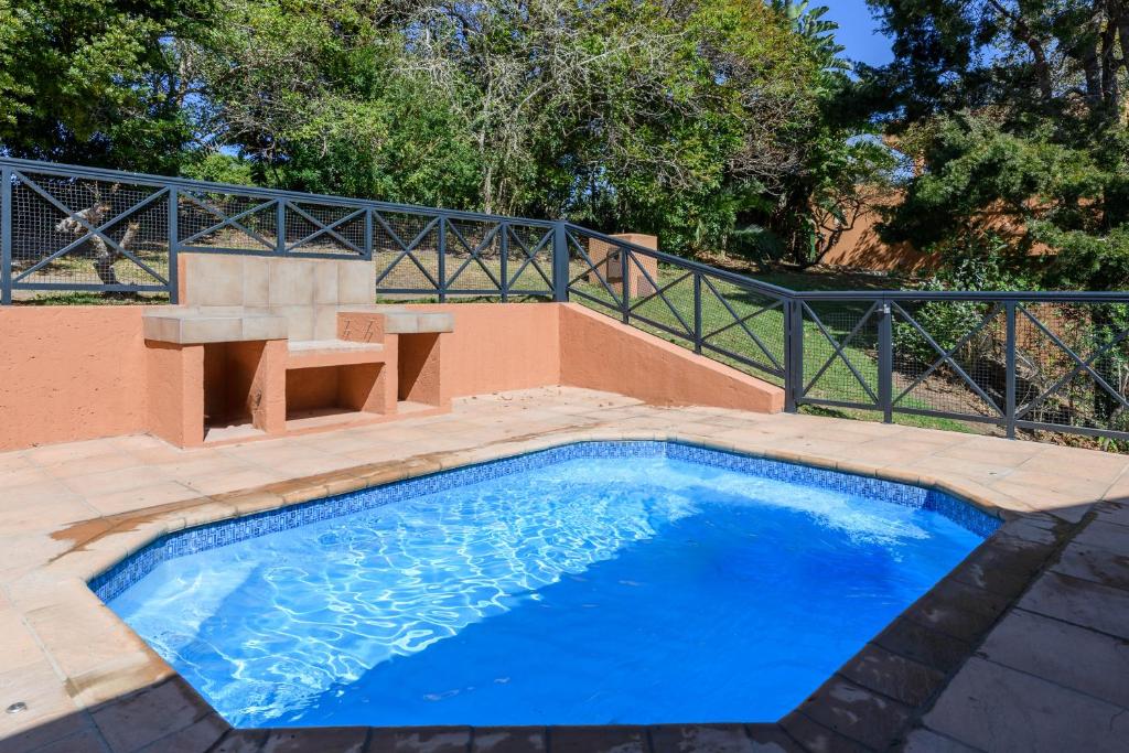 绍斯布鲁姆San Lameer Villa 10432 - 5 Bedroom Deluxe - 10 pax - San Lameer Rental Agency的一个带长凳和围栏的蓝色小游泳池