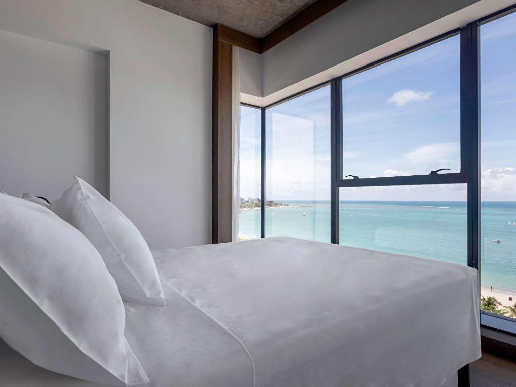 马塞约ibis Styles Maceió Pajuçara的卧室设有白色床,享有海景