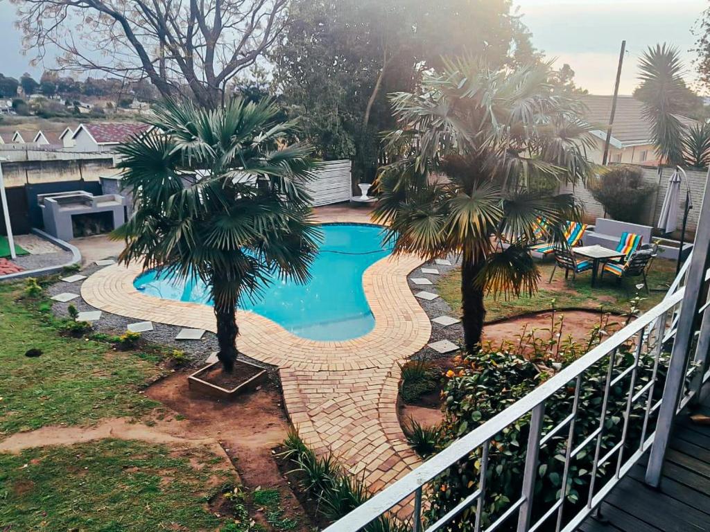 乌姆塔塔Adante Lodge & Conferencing的庭院内一座游泳池,两棵棕榈树