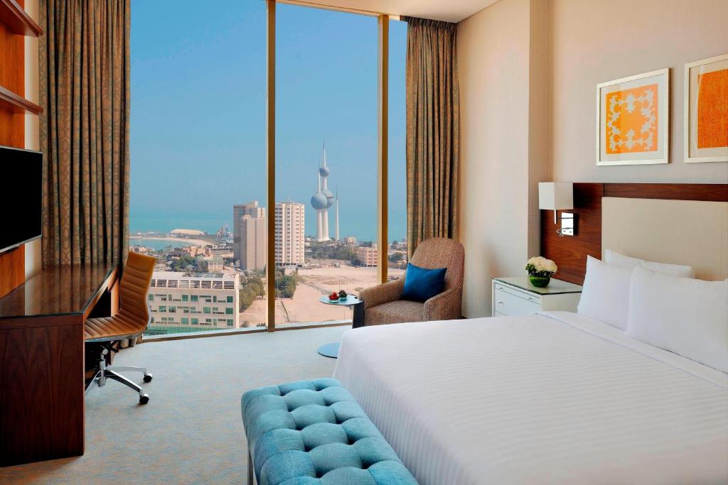 科威特科威特市万豪原住酒店的酒店客房设有一张床、一张书桌和一个大窗户。