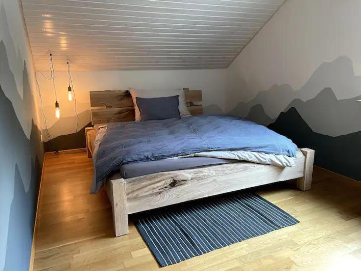 WaldHerzliches Zimmer im Zürcher Oberland的卧室配有一张挂有山壁画的床。