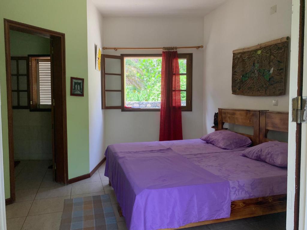 PaulWahnon Guesthouse的一间卧室配有一张带紫色床单的床和窗户。
