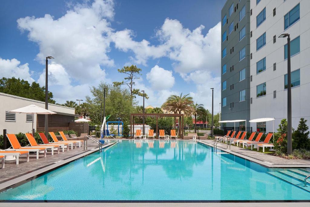 奥兰多Aloft Orlando International Drive的一座带椅子的大型游泳池和一座建筑