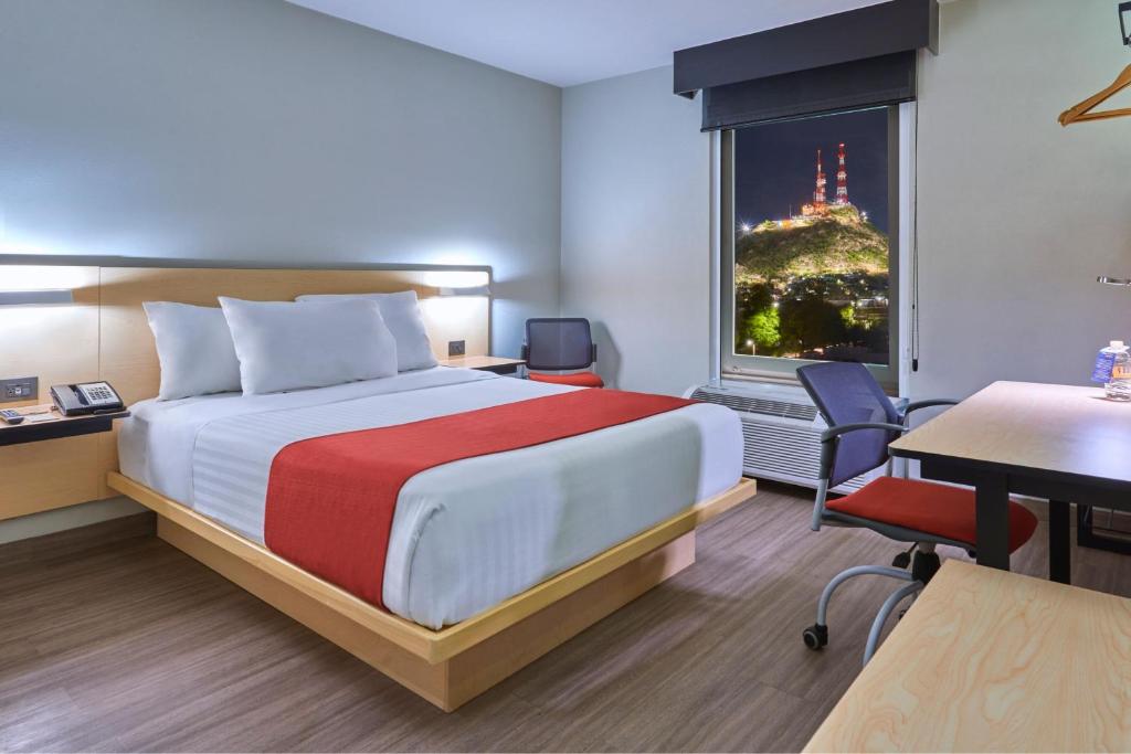 埃莫西约埃莫西约城市通酒店的配有一张床、一张书桌和一扇窗户的酒店客房