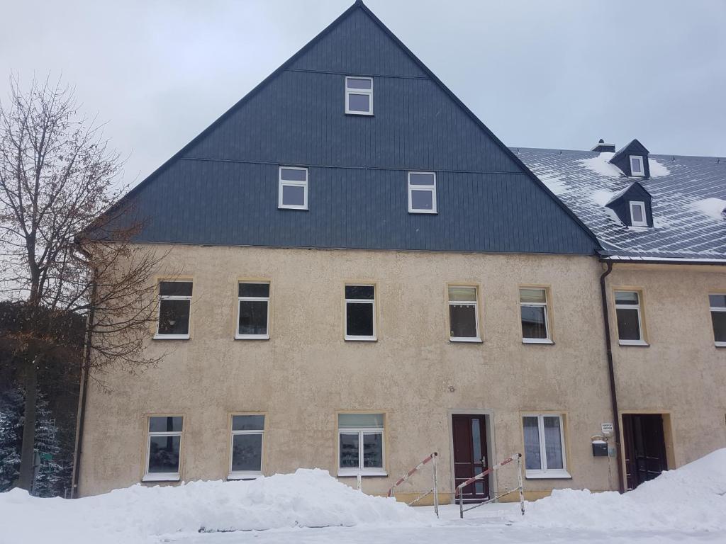 JöhstadtDie Alte Bäckerei的雪中黑色屋顶的大房子