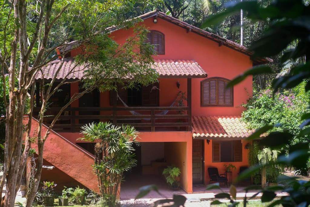 佩尼多Casa em penedo com cachoeira的前面有树木的红房子