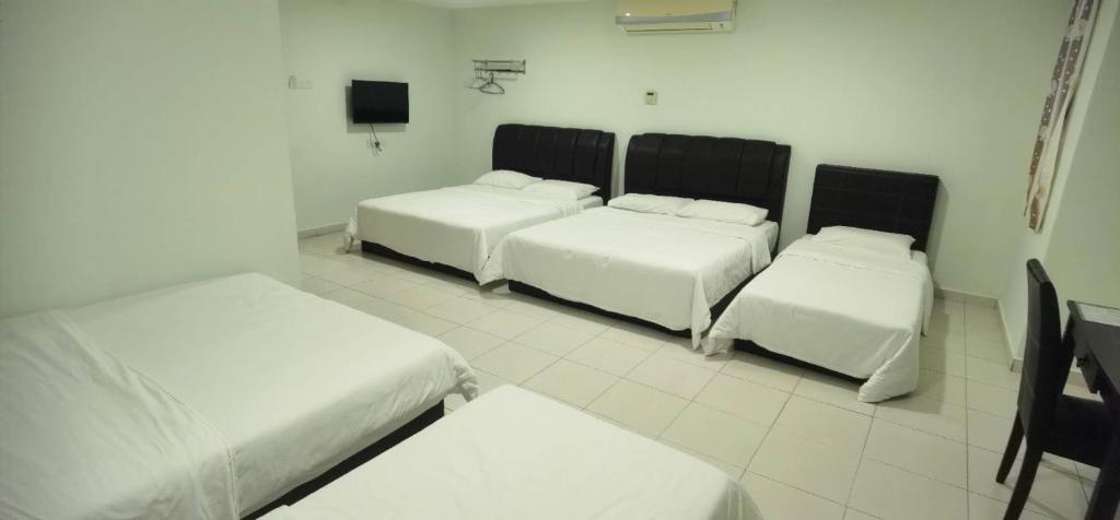 马六甲The Glorious Straits Hotel的一间设有三张床和一台电视的房间