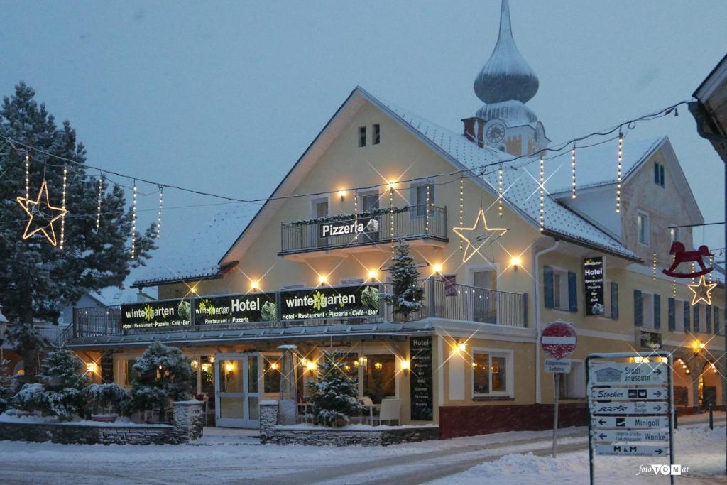 斯拉德明Hotel Wintergarten的雪中带圣诞灯的建筑