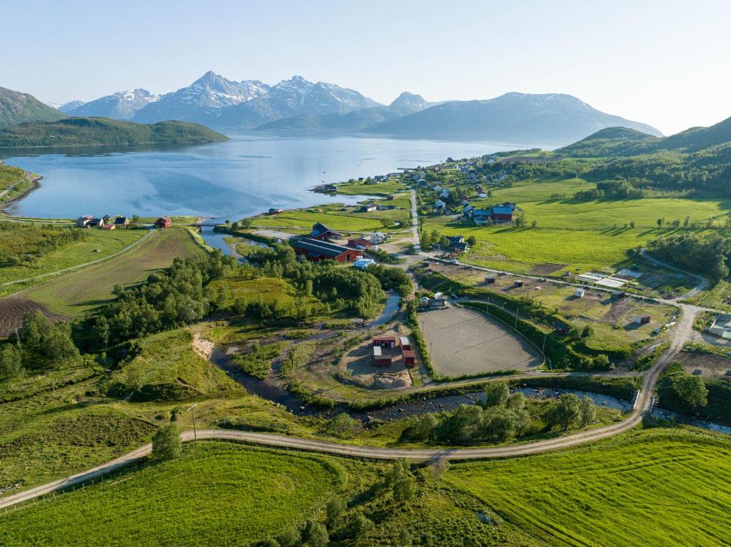 KvaløyaStorjord Farmstay Ranchhouse的享有湖泊的空中美景,背景为山脉