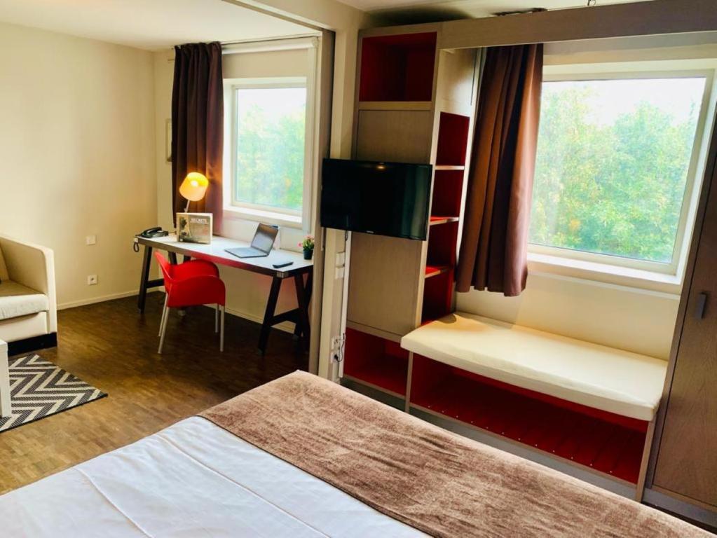 鲁瓦西昂法兰西阿克蒂苏尔斯施坦丁套房酒店的客房设有一张床、一张桌子和一台笔记本电脑