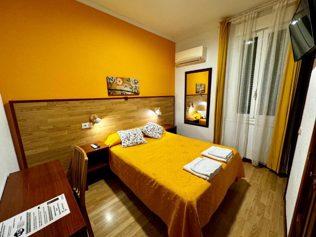 马德里爱迪瑞旅馆 的黄色卧室配有床和书桌