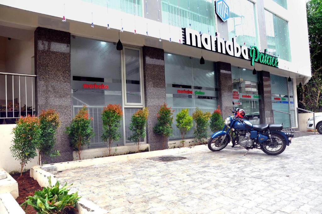 科泽科德MARHABA PALACE的停在大楼前的一辆蓝色摩托车