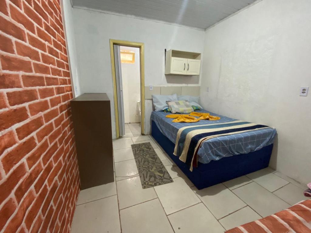伊达贾伊Itajai Quartos e Suites的一间小卧室,配有床和砖墙