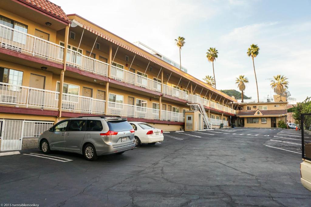 洛杉矶好莱坞拉布雷亚酒店 的两辆汽车停在酒店门前的停车场