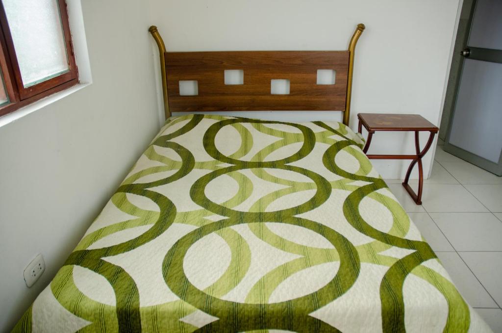 特鲁希略Ugarte Street的一间卧室配有一张带绿色和白色毯子的床
