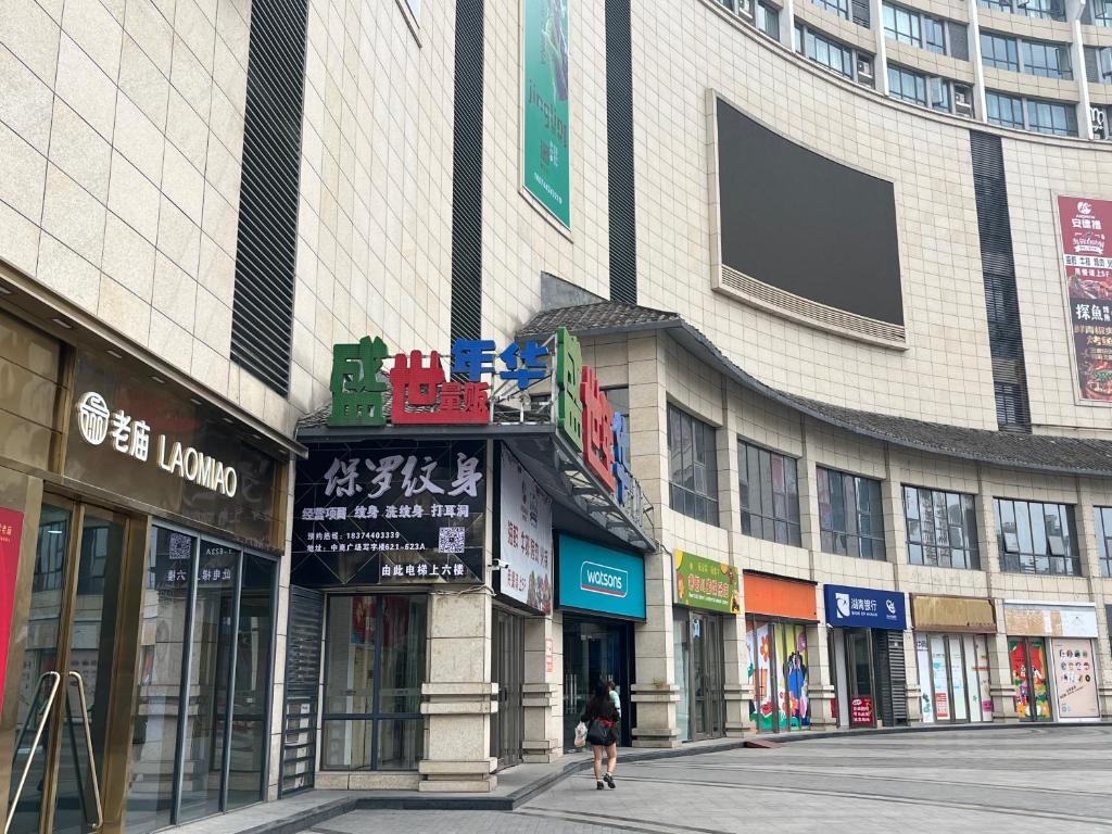 张家界Zhangjiajie ViVi Boutique Hotel的走在建筑物前的街道上的女人