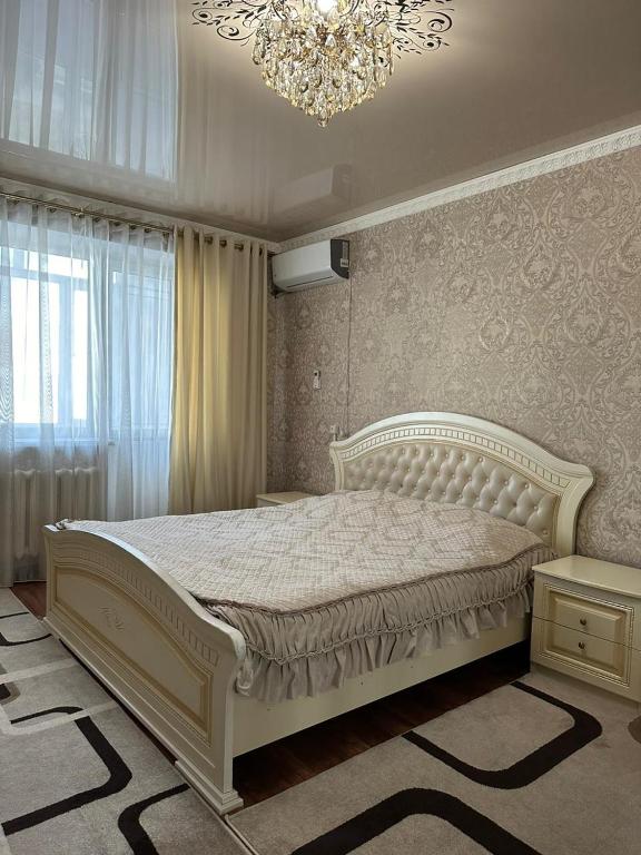 塔拉兹Квартира люкс的卧室配有白色的床和吊灯。