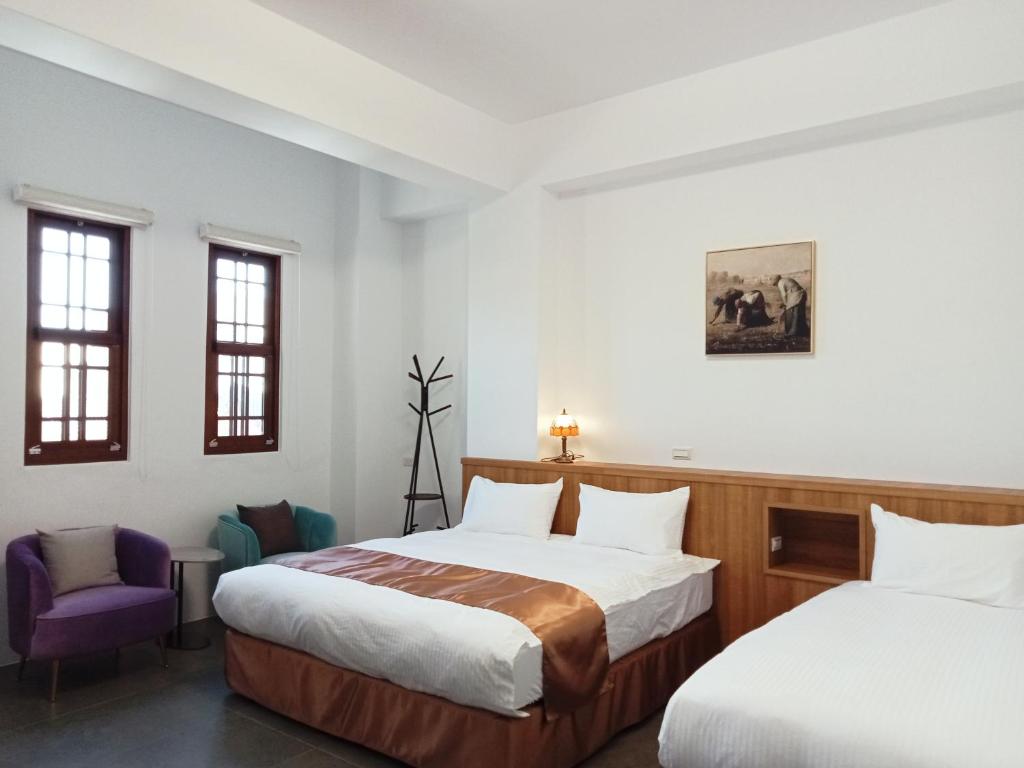 鹿港镇洛津驿民宿的一间卧室配有两张床和一张紫色椅子