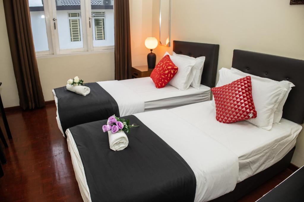 关丹Sweet Inn Guest House的两张位于酒店客房的床,配有红色和白色枕头
