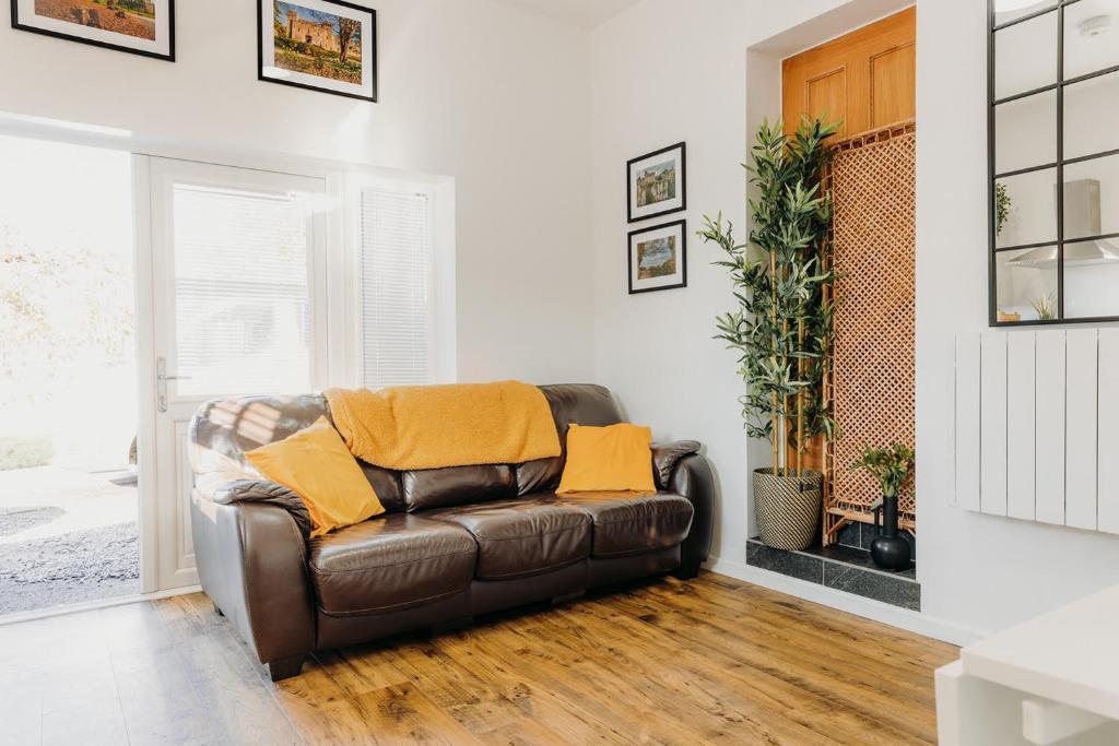 卡尔迪科特Superb Tiny Home in Caldicot with Parking的客厅配有带黄色枕头的棕色皮沙发