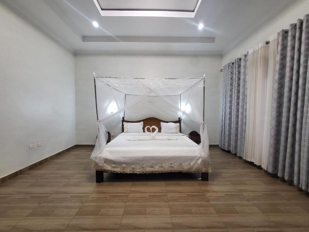 基加利ASMERA GUEST HOUSE的一间卧室配有一张带天蓬的白色床