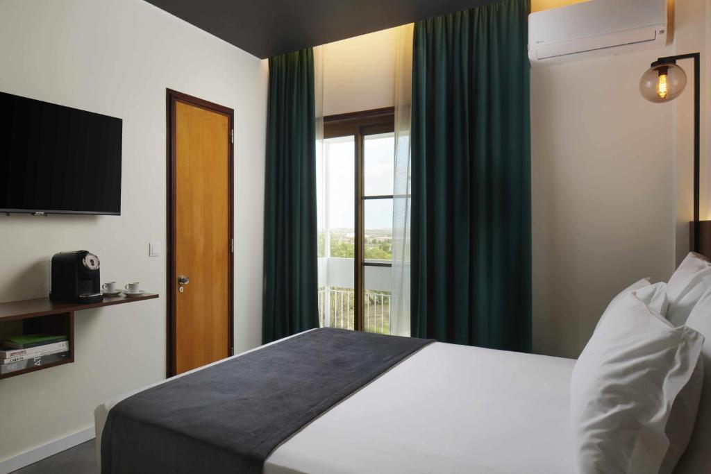 法鲁Alto House Faro AL de Assinatura Modernista的酒店客房设有床和窗户。