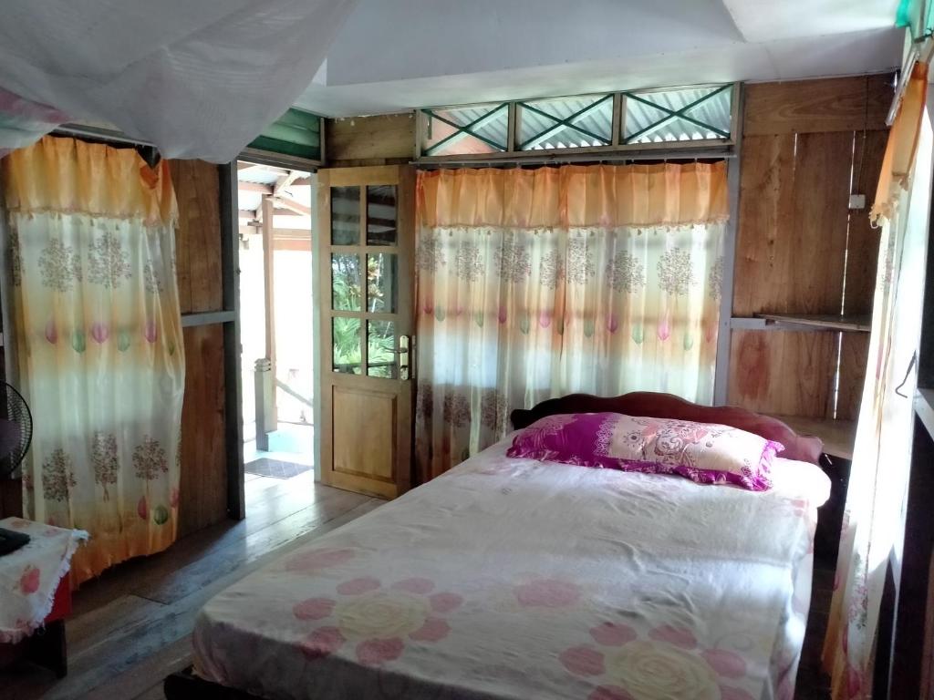 NgurblutDelima Cottage, Ngurbloat Beach的一间带床的卧室,位于带窗帘的房间