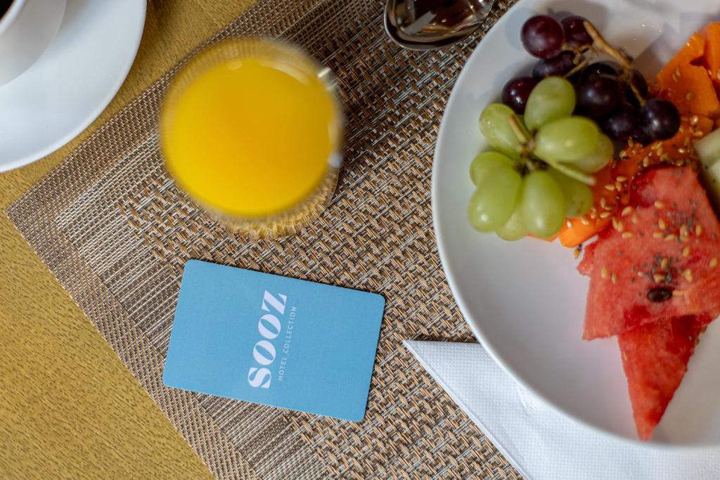 圣保罗Sooz Hotel Collection的一杯橙汁和葡萄的食品
