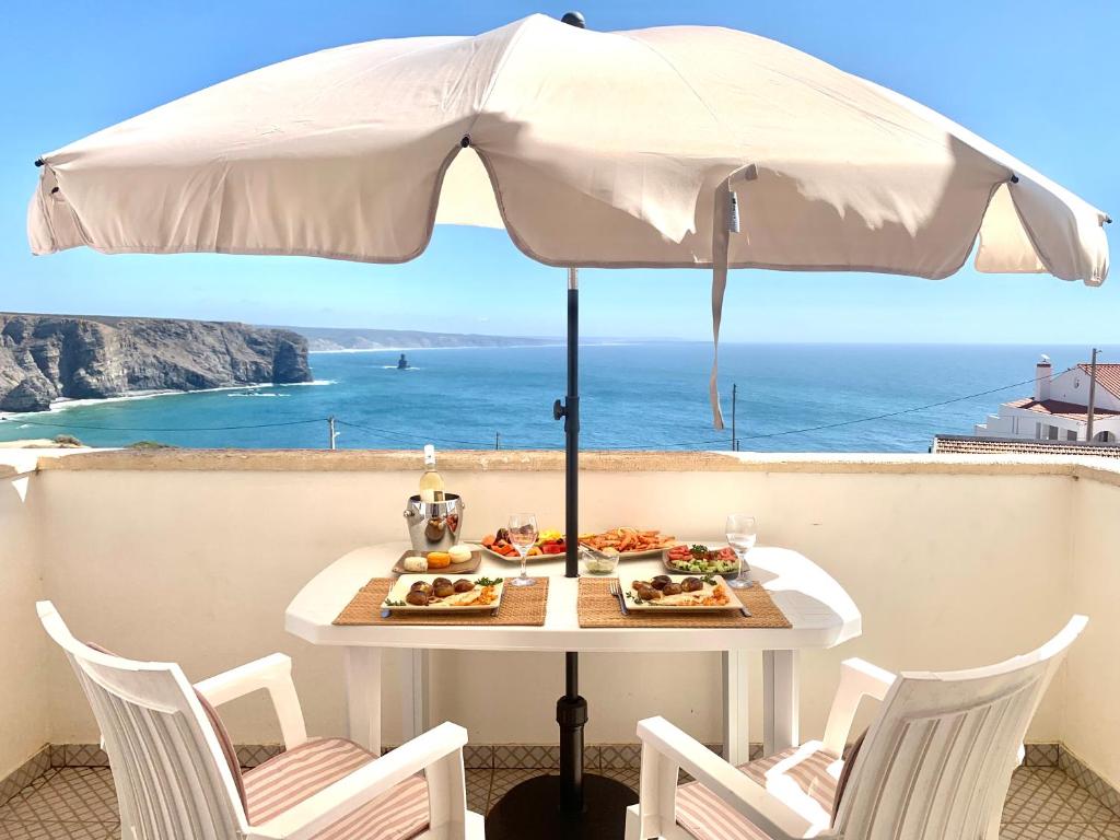 阿尔热祖尔Apartment Praia Arrifana with BALCONY and SEA VIEW的一张桌子,上面有盘子和一把雨伞