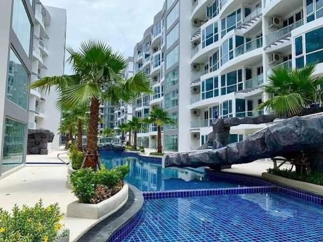 芭堤雅市中心Grand Avenue Pattaya的一座楼前棕榈树游泳池