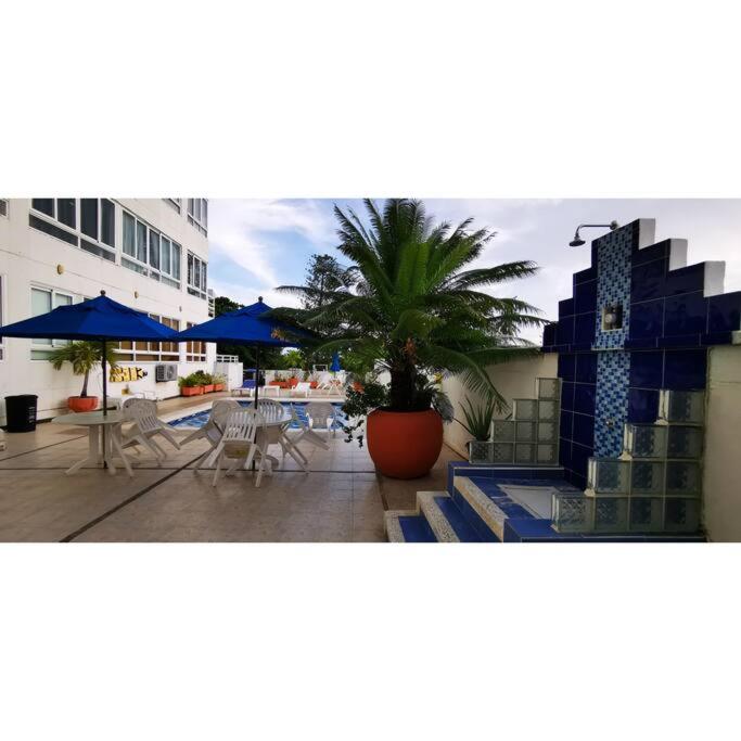 圣安德烈斯ocean apartment 310的一个带棕榈树、桌子和遮阳伞的庭院