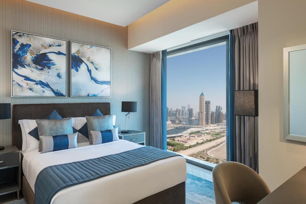 迪拜DAMAC Maison Aykon City Dubai的酒店客房设有一张床和一个大窗户